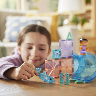 Magna-Tiles Dolphin Bay™ 13-Piece Set
Child playing with transparent blue toy figures on a wooden table.