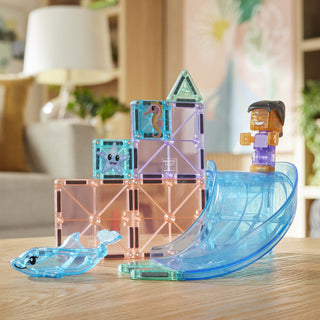 Magna-Tiles Dolphin Bay™ 13-Piece Set
Transparent building blocks with characters and a shark toy on a wooden surface.