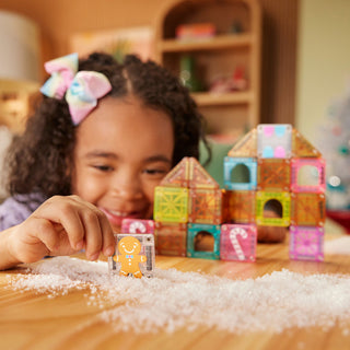 Magna-Tiles microMAGS Gingerbread House 24-Piece Travel Set
Child playing with colorful magnetic building blocks on a wooden table.