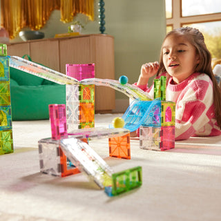 Magna-Tiles Rail Racers™ Max 80-Piece Set
Child playing with colorful magnetic building blocks on a table.