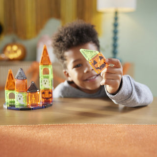 Magna-Tiles microMAGS Spooky 24-Piece Travel Set
Child playing with Halloween-themed building blocks on a table.