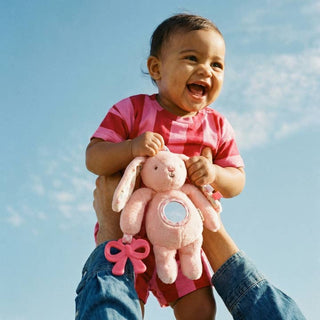 Itzy Ritzy Bitzy Traveler™ - Pink Bunny
Child holding a pink plush toy against a blue sky