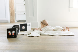 Paige Tate Baby's Tummy Time Sports: A Sports Board Book For Babies
Baby lying on a blanket with educational cards on a wooden floor