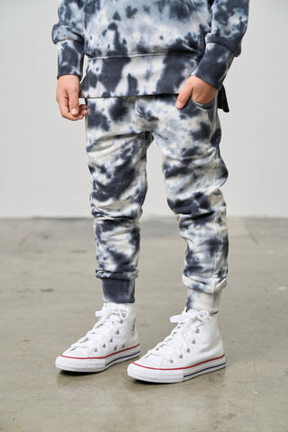 Little Bipsy Marble Jogger - Blue
Person wearing tie-dye pants and white high-top sneakers on a plain background