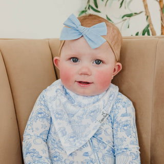 Copper Pearl Bandana Bib Set - Vintage Carnival
A baby wearing a light blue patterned bib and matching headband with a large bow, sitting on a beige armchair.