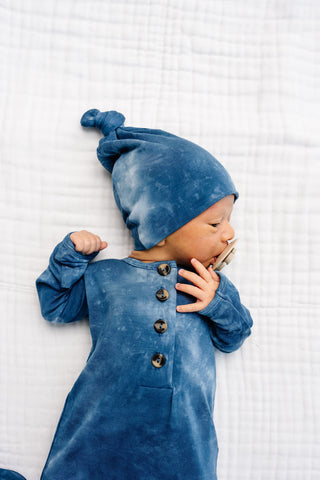Lou Lou and Company Top Knot Hat - HeathBaby wearing a blue outfit and hat on a white textured surface