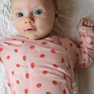 Bonsie Footie - Strawberries
Baby wearing a pink outfit with strawberry pattern on a white blanket