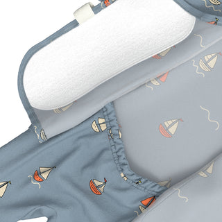 Bonsie Footie - Ahoy Baby
close-up of a baby clothing or bedding set with a light blue fabric printed with small sailboat motifs, a white padded insert, and a white elastic trim, shown on a white background.