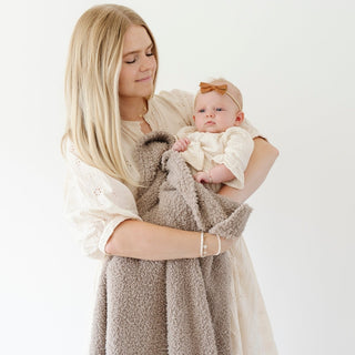 Saranoni Bamboni® Receiving Blanket - Taupe
Woman holding a baby wrapped in a brown blanket against a white background