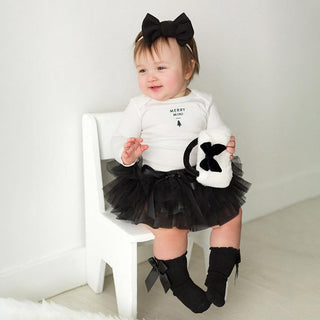 Stephan Baby Plush Rattle Purse - Bow
Baby in a black and white outfit with a tutu and bow tie, sitting on a white chair.