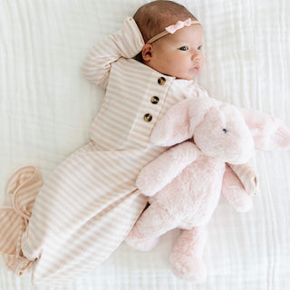 Lou Lou and Company Ribbed Knotted Gown - Harper
Baby in a striped outfit holding a pink plush toy on a white background