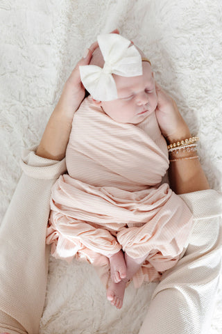 Lou Lou and Company ribbed swaddle blanket in Rosie color, soft and cozy for newborns, with a textured ribbed fabric design.