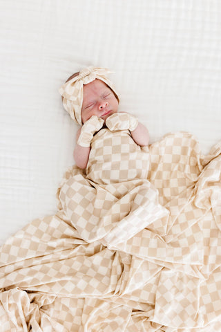 Lou Lou and Company Swaddle Blanket - Austin
Newborn baby wrapped in a beige checkered blanket with matching headband on a white background
