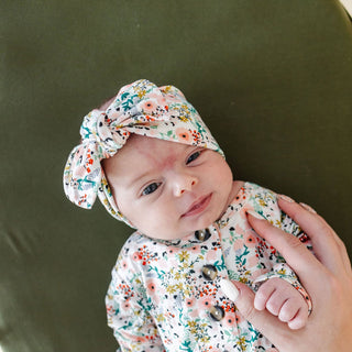 Lou Lou and Company Headband - Millie
Baby wearing a floral headband and onesie, held by a hand against a green background