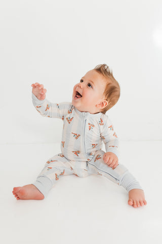 In My Jammers Zipper Romper - Little Sailboat
Baby wearing a light gray onesie with a pattern, sitting on a white surface.