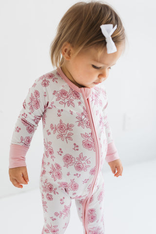 In My Jammers Blush Garden Zipper Romper
Child wearing a pink and white floral onesie on a white background