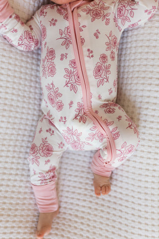 In My Jammers Blush Garden Zipper Romper
Baby in a pink floral onesie lying on a textured surface