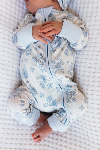 In My Jammers Blue Rose Garden Zipper Romper
Baby wearing a floral onesie on a textured surface
