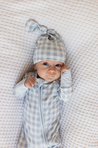 In My Jammers Blue Gingham Newborn Hat
Baby wearing a blue checkered outfit and hat lying on a textured blanket