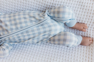 In My Jammers Blue Gingham Zipper Romper
Baby in blue checkered outfit lying on a textured surface