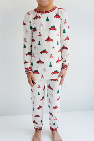 In My Jammers Red Holly Jolly Cruisers Two Piece Set
Child wearing Christmas-themed pajamas with red cars and green trees on a white background