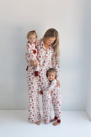 In My Jammers Merry Little Bows Zipper Romper
Woman and two children wearing matching pajamas with a red and white pattern on a white background