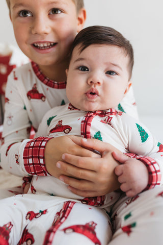 In My Jammers Red Holly Jolly Cruisers Zipper Romper
Two children in matching Christmas-themed pajamas holding each other.