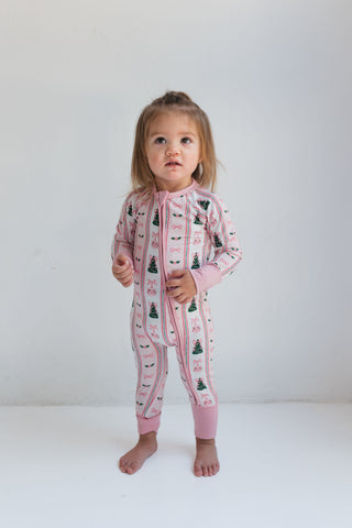 In My Jammers Pinkmas Zipper Romper
Child wearing a pink onesie with tree pattern on a white background