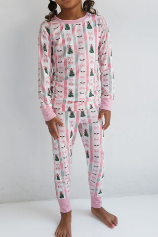 In My Jammers Pinkmas Two Piece Set 
Child wearing pink pajamas with Christmas tree pattern on a white background