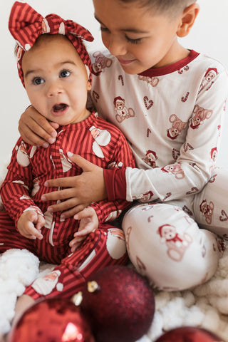In My Jammers Santa Headband
Two children in matching pajamas with Christmas ornaments around them.