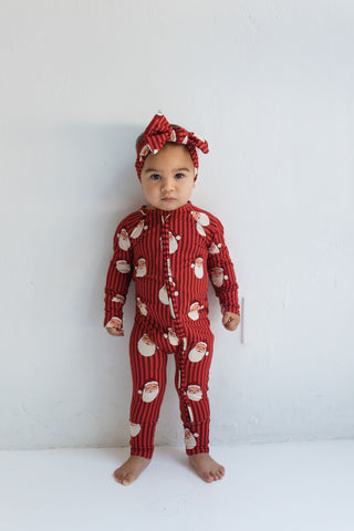 In My Jammers Santa Zipper Romper
Baby wearing a red Santa Claus pajama set with a matching headband on a white background