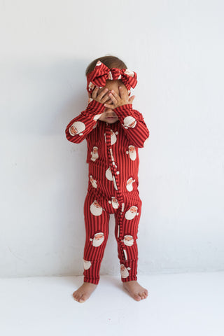 In My Jammers Santa Zipper Romper
Child wearing a red pajama set with Santa Claus pattern on a white background