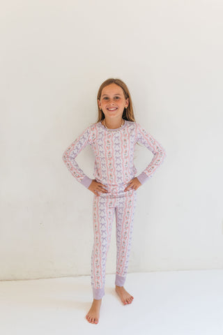 In My Jammers Two Piece Set - Purple Amelia Bow
Young girl wearing a patterned pajama set on a white background