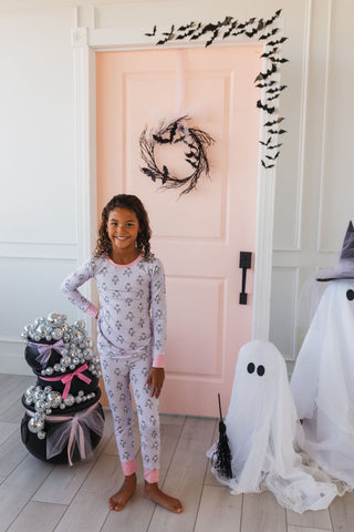 In My Jammers Ballerina Ghost Two Piece Set Child in Halloween-themed pajamas standing in a room with ghost decorations and a pink door.