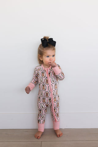 In My Jammers Howl-O-Ween Pups Zipper Romper Child wearing a patterned onesie with pink accents against a white background
