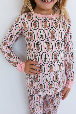 In My Jammers Howl-O-Ween Pups Two Piece Set Child wearing a pink onesie with dog pattern on a white background