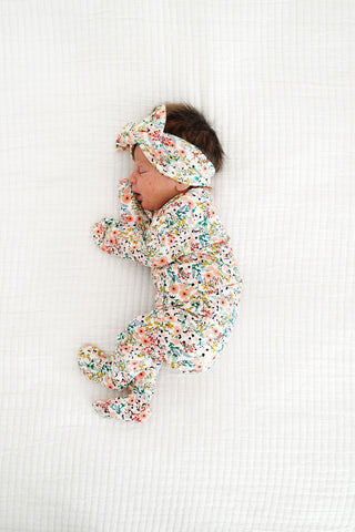 Lou Lou and Company Top and Bottoms - Millie
Baby in a floral outfit and headband lying on a white textured surface