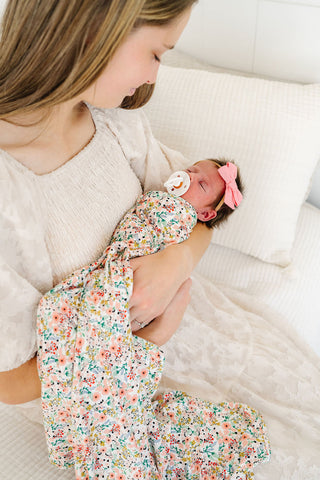 Lou Lou and Company Swaddle Blanket - Millie
Woman holding a newborn baby wrapped in a floral blanket on a white couch.