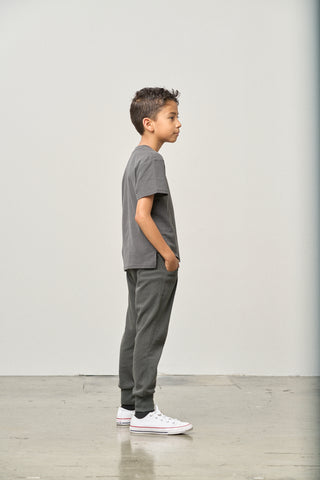 Little Bipsy Elevated Tee - Shadow
Young boy standing against a plain white wall wearing a gray t-shirt and pants.