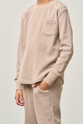 Little Bipsy Waffle Top - Mushroom
Person wearing a beige long-sleeve shirt and pants on a plain background