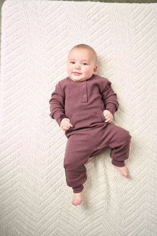 Little Bipsy Waffle Romper - Huckleberry
Baby in a purple onesie lying on a textured white blanket