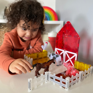 Magna-Tiles Farm™ 25-Piece Set
Child playing with farm toy set including a horse, barn, and animals on a table.