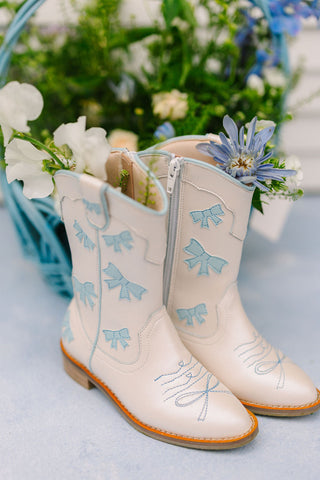 Wild & Rae cowgirl boots in baby blue with decorative bow, stylish ankle boots for girls featuring Western-inspired design.