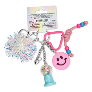 Iscream Gumball Machine Bag Charm
A novelty keychain set with a pink smiley face charm, a pink carabiner, a small gumball machine charm, a pink beaded cord, and a silver tinsel pom-pom, attached to a retail card by The Moon Press.