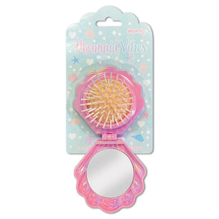 Open package showing Iscream Mermaid Vibes pop-up shell mirror and hairbrush with mermaid-themed design and pastel colors.