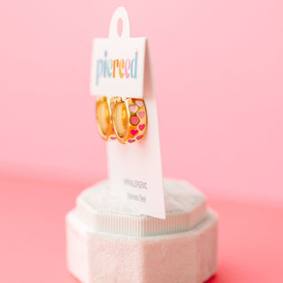 Pierced Co. Chunky Pink Heart Ombré Huggies
Pair of gold earrings with colorful heart design on a 'pierced' branded card against a pink background