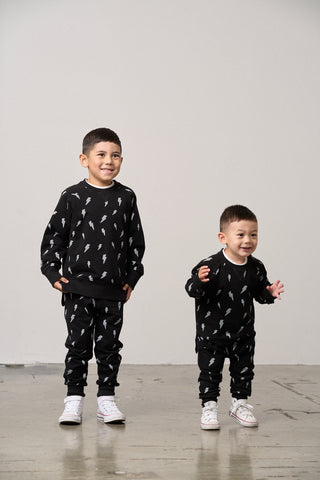 Little Bipsy Lightning Bolt Pullover - Black
Little Bipsy Lightning Bolt Jogger - Black
Two children wearing matching black outfits with white patterns on a plain background