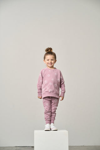 Little Bipsy Smiley Pullover - Dusty Purple
Child wearing a pink outfit on a white pedestal against a plain background