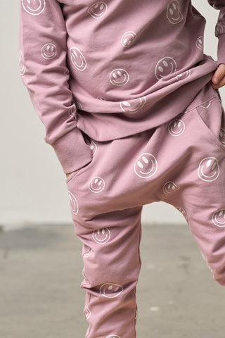 Little Bipsy Smiley Jogger - Dusty Purple
Person wearing a pink tracksuit with smiley face patterns on a neutral background