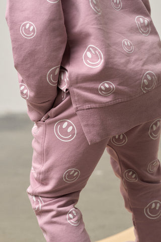 Pink sweatshirt and pants with smiley face patterns on a neutral background